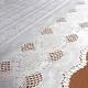 Close up detail of a white table runner made from vinyl with lace details and scalloped edges.