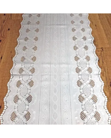 Close up detail of a white table runner made from vinyl with lace details and scalloped edges.