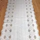 Close up detail of a white table runner made from vinyl with lace details and scalloped edges.