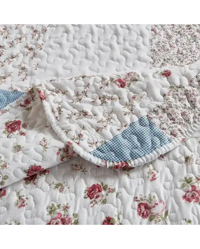 Close-up of a floral quilt, showcasing a small rose print with a delicate stitching texture.