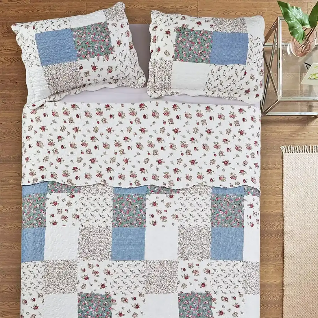 Top view of a floral patchwork quilt on a bed, complemented by matching decorative pillows.