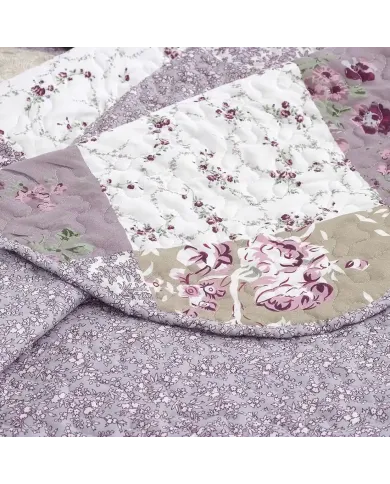 Close-up van een bloemen sprei, met een patchwork lavendelprint met een verfijnde stikstructuur.