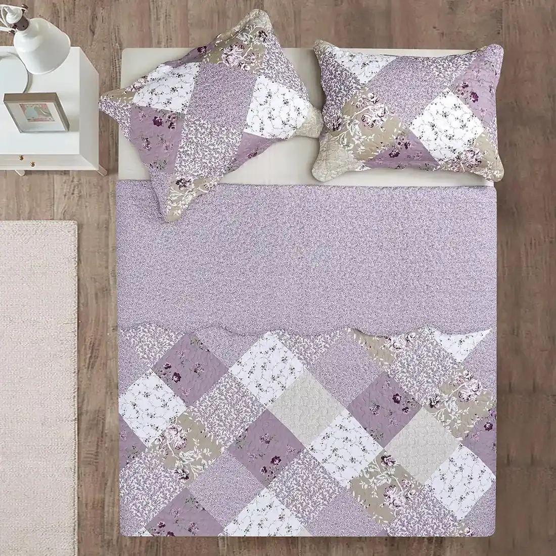 Top view of a patchwork quilt on a bed, complemented by matching decorative pillows.