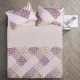 Bovenaanzicht van een bedsprei oud roze in patchwork op een bed, aangevuld met bijpassende sierkussens.