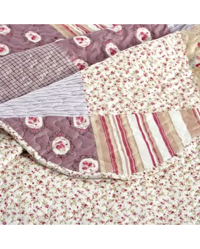 Close-up van een bedsprei oud roze, met gedempte roze en mauve tinten en een fijne stiktextuur.