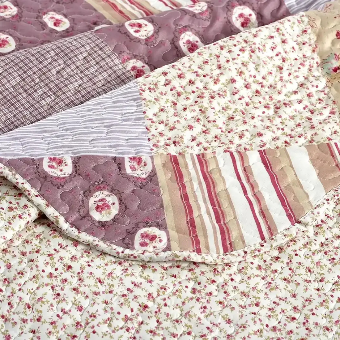 Close-up van een bedsprei oud roze, met gedempte roze en mauve tinten en een fijne stiktextuur.