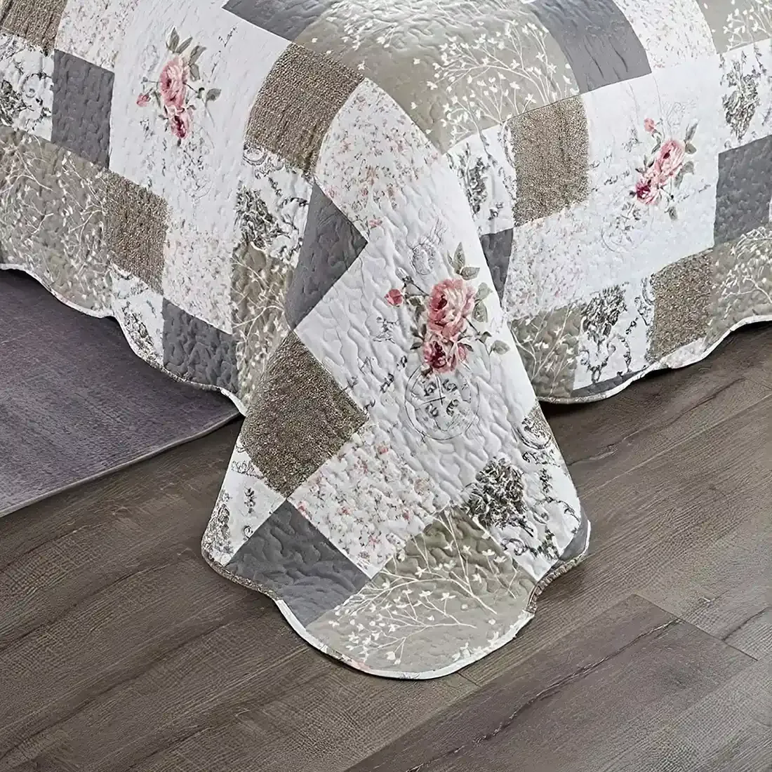 Een patchwork bedsprei beige en wit gekleurd, met bloemmotieven, vermicellistiksels en geschulpte randen.