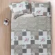 Quilted bedspread with a floral patchwork design in beige, complemented by matching decorative pillows.