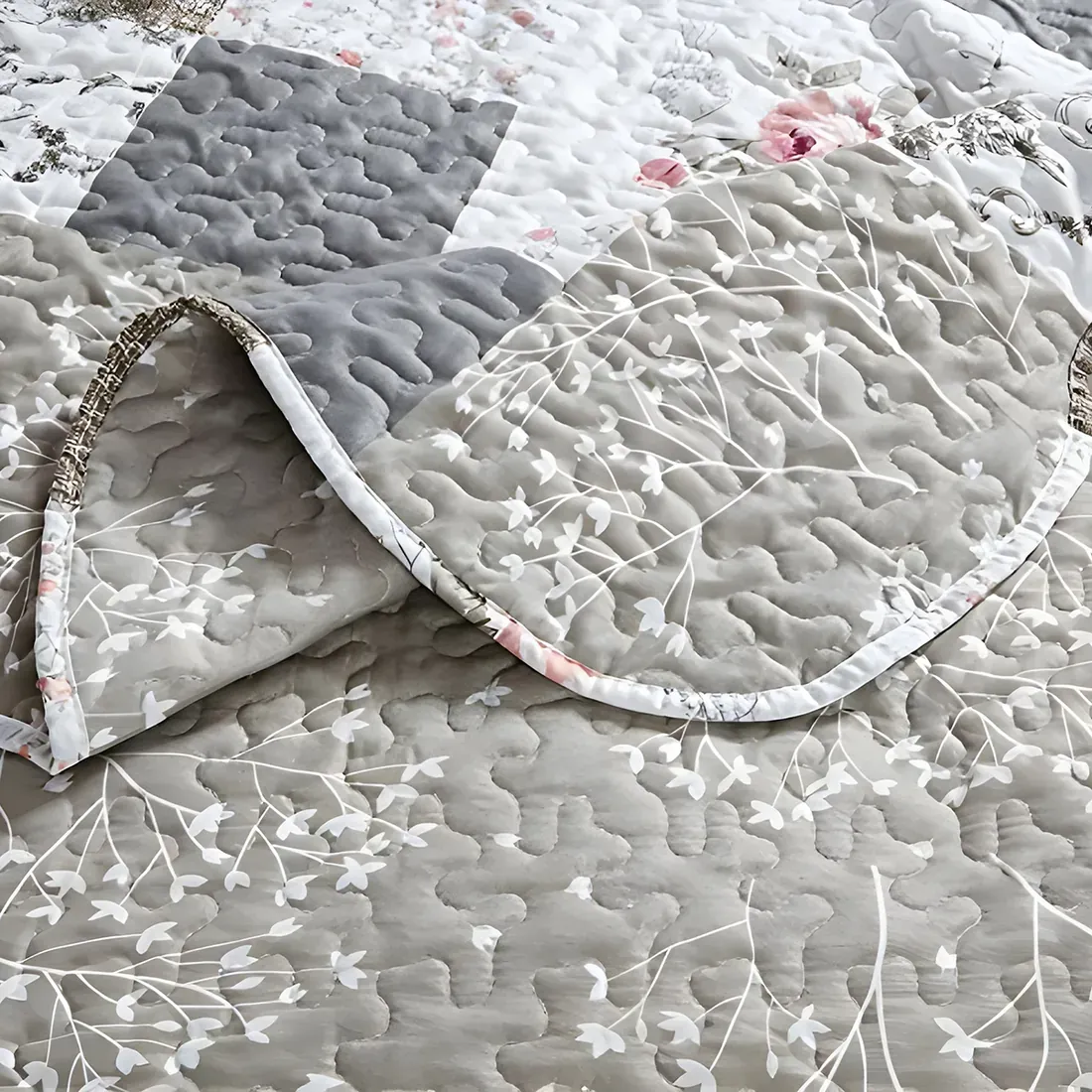 Close-up of a floral and patterned quilt in beige, showcasing soft beige and whites with a delicate stitching texture.