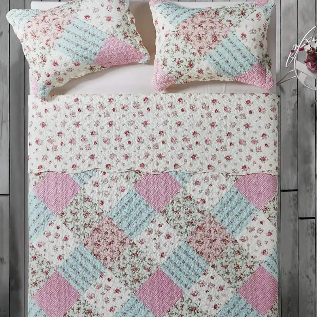 Top view of a patchwork pink quilt on a bed, complemented by matching decorative pillows.