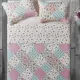 Top view of a patchwork pink quilt on a bed, complemented by matching decorative pillows.
