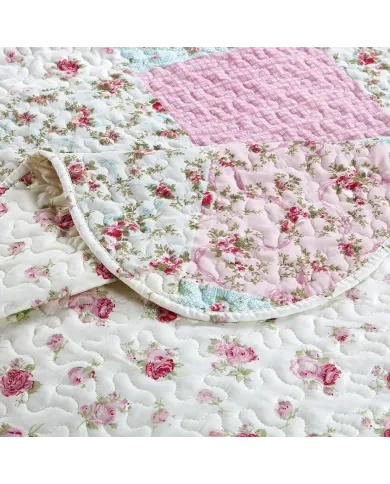 Close-up of a pink quilt, showcasing pink patchwork with a delicate stitching texture.