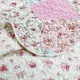Close-up of a pink quilt, showcasing pink patchwork with a delicate stitching texture.