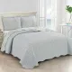 Showcasing the reverse design of the blue quilt, a diamond pattern with a small floral print, paired with matching pillows.