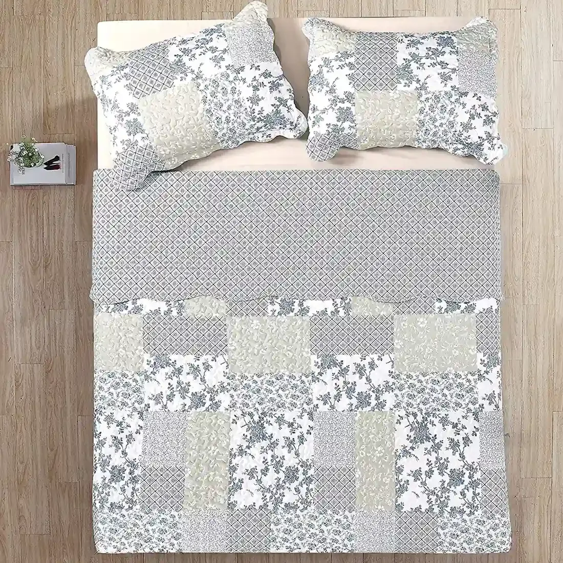 Top view of a patchwork blue quilt on a bed, complemented by matching decorative pillows.