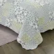 Detail of a blue bedspread showcasing floral patchwork squares, vermicelli stitching and scalloped edging.