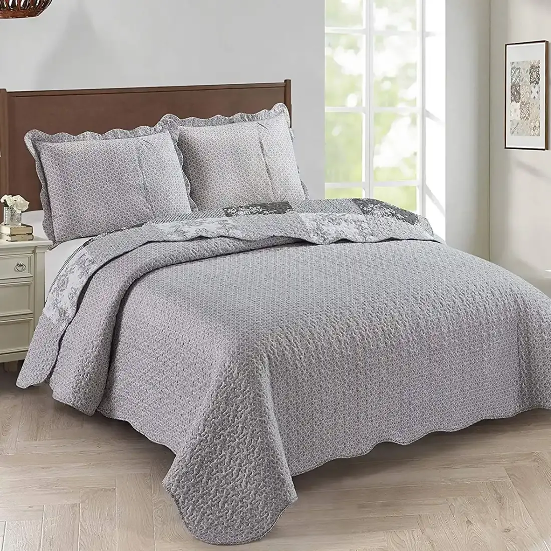 Showcasing the Toile de Jouy patchwork design of the grey quilt, paired with matching pillows.