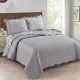 Showcasing the Toile de Jouy patchwork design of the grey quilt, paired with matching pillows.
