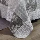 Detail van een grijze bedsprei met toile-bloempatroon, vermicelli-stiksel en schulprand.