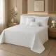 Rustgevende slaapkamer met een bedsprei wit en bijpassend beddengoed in natuurlijk licht.