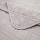 Close-up of a grey bedspread with a delicate stitching texture.