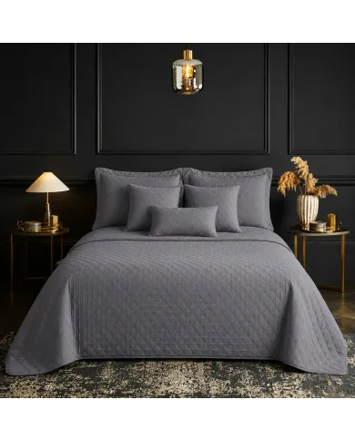 Een netjes opgemaakt bed met een bedsprei grijs in een kamer met twee nachtkastjes.