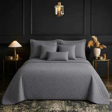 Een netjes opgemaakt bed met een bedsprei grijs in een kamer met twee nachtkastjes.