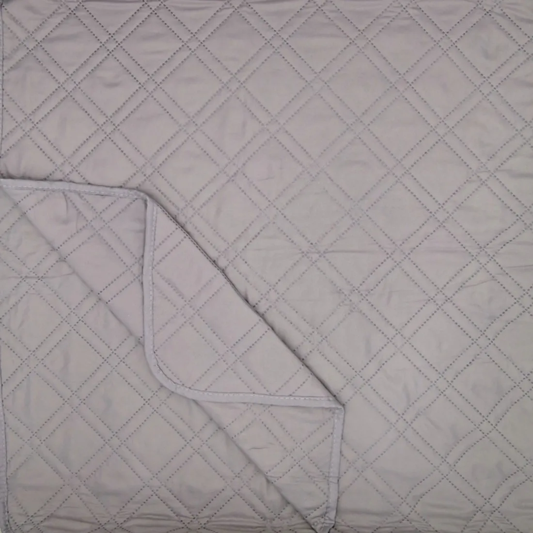 Close-up of a grey quilt showcasing a double diamond pattern.
