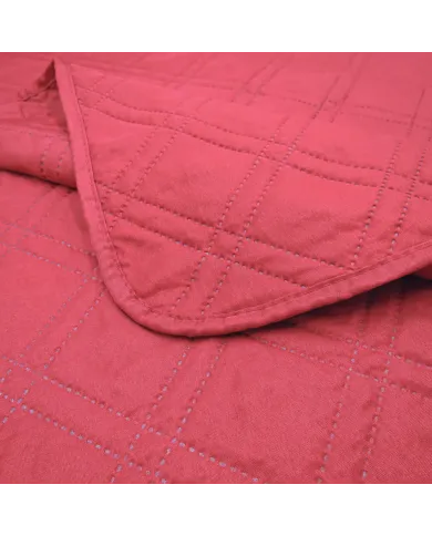 Close-up van een bedsprei rood met een delicaat stiksel.