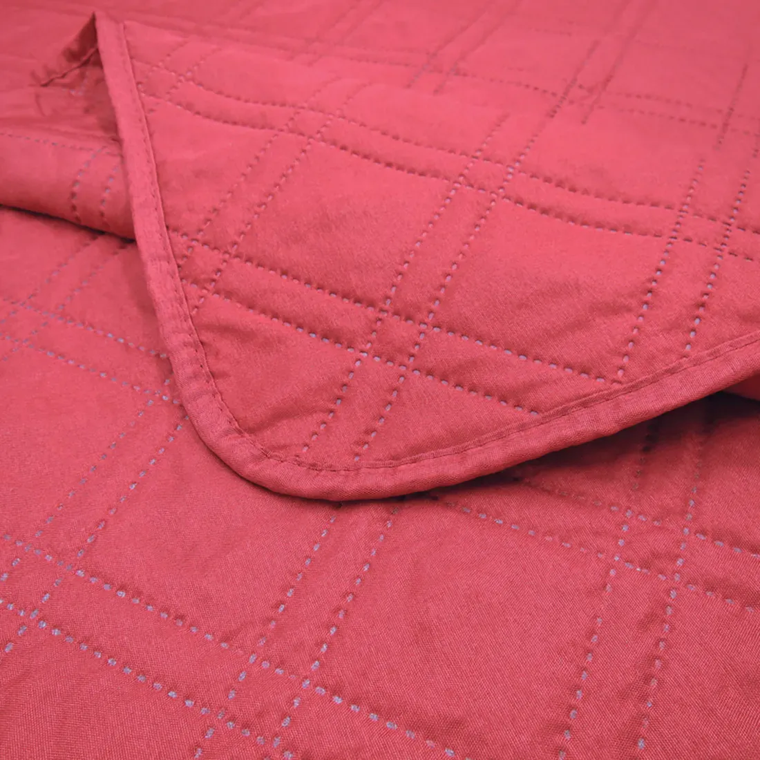 Close-up of a red bedspread with a delicate stitching texture.