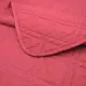 Close-up of a red bedspread with a delicate stitching texture.