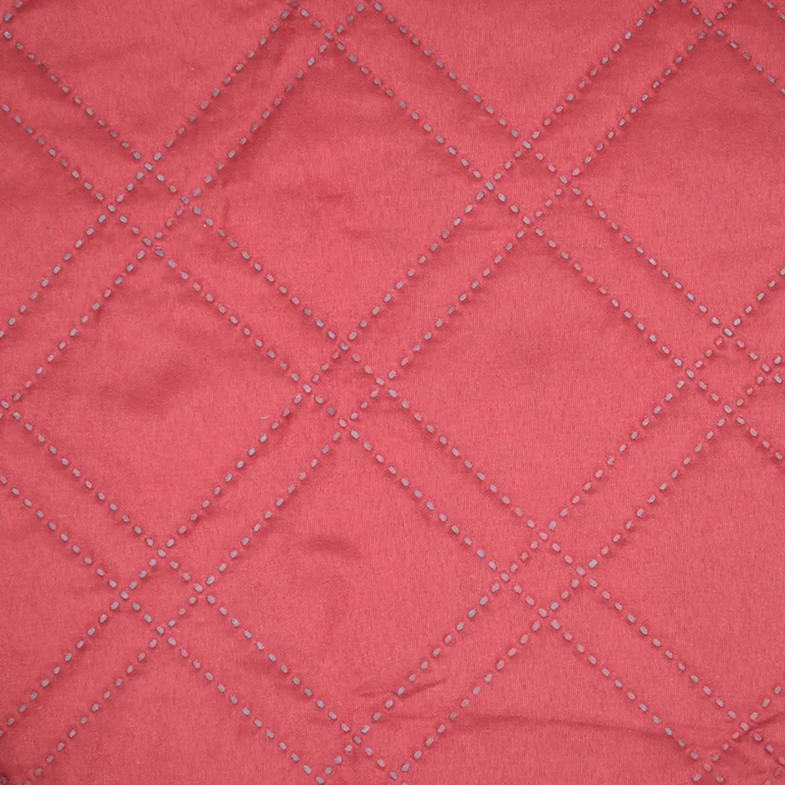 Close-up of a red bedspread showcasing a double diamond pattern.