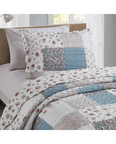A blue pillowcase with matching bedspread on a cozy bed by a window.
