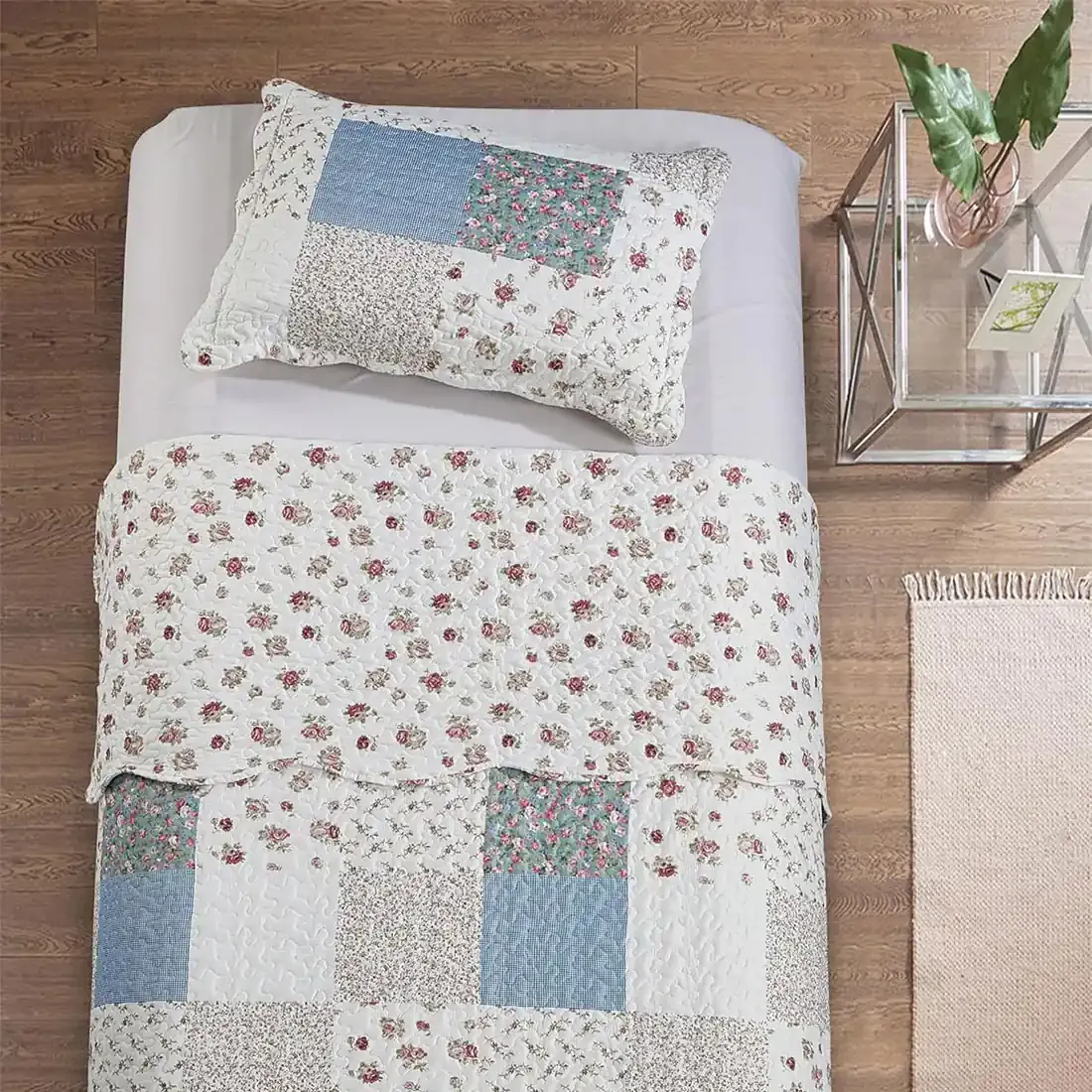 Top view of a blue pillow on a bed, complemented by a matching patchwork quilt.