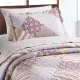 A pink pillowcase that combines floral, stripe, and check patch tiles with matching quilt on a cosy bed.