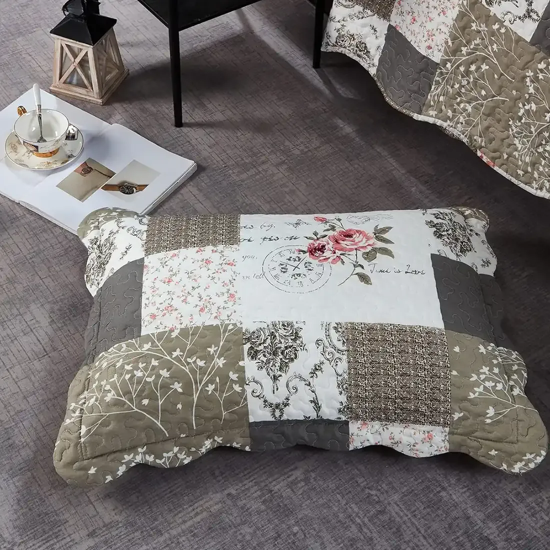A beige patchwork pillowcase in Vintage Rose patterns rests on a textured grey floor.