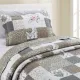 Een kussensloop beige met bijpassende sprei op een knus bed bij het raam.