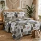 Kussensloop beige an patchwork sprei met bloemmotief op een bed in een lichte gedecoreerde kamer.