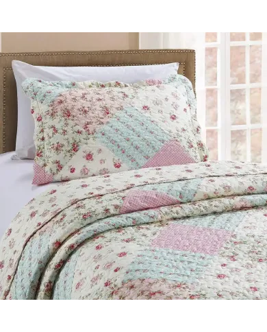 Een roze kussensloop met bijpassende sprei op een knus bed bij het raam.
