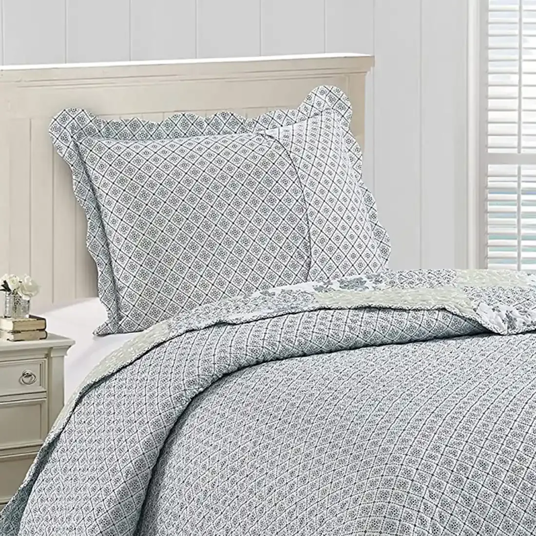Het omkeerbare ontwerp van de kussensloop wit en blauw, een kleine bloemenprint, op een netjes opgemaakt bed.