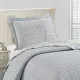 Het omkeerbare ontwerp van de kussensloop wit en blauw, een kleine bloemenprint, op een netjes opgemaakt bed.