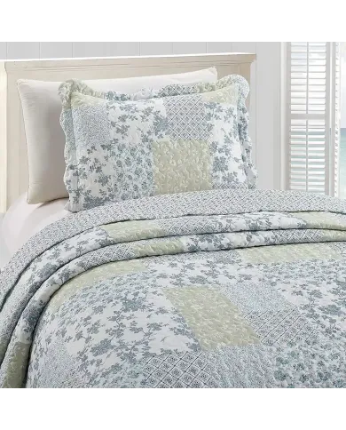 Een kussensloop wit en blauw met bijpassende sprei op een knus bed bij het raam.