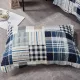 A blue patchwork pillowcase in Blue Loft patterns rests on a textured grey floor.
