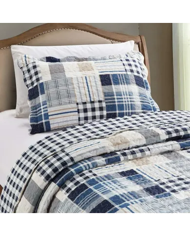 Een blauwe kussensloop met bijpassende sprei op een netjes opgemaakt bed.