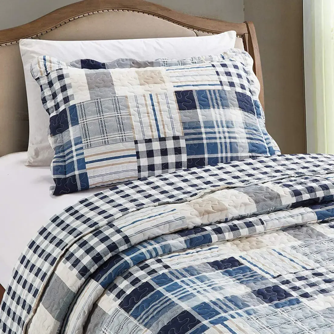 Een blauwe kussensloop met bijpassende sprei op een netjes opgemaakt bed.