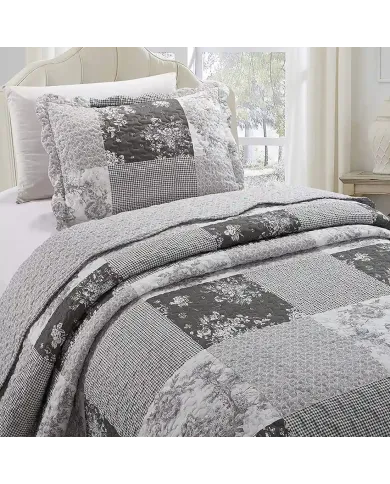 Een grijze kussensloop met bijpassende sprei op een knus bed bij het raam.