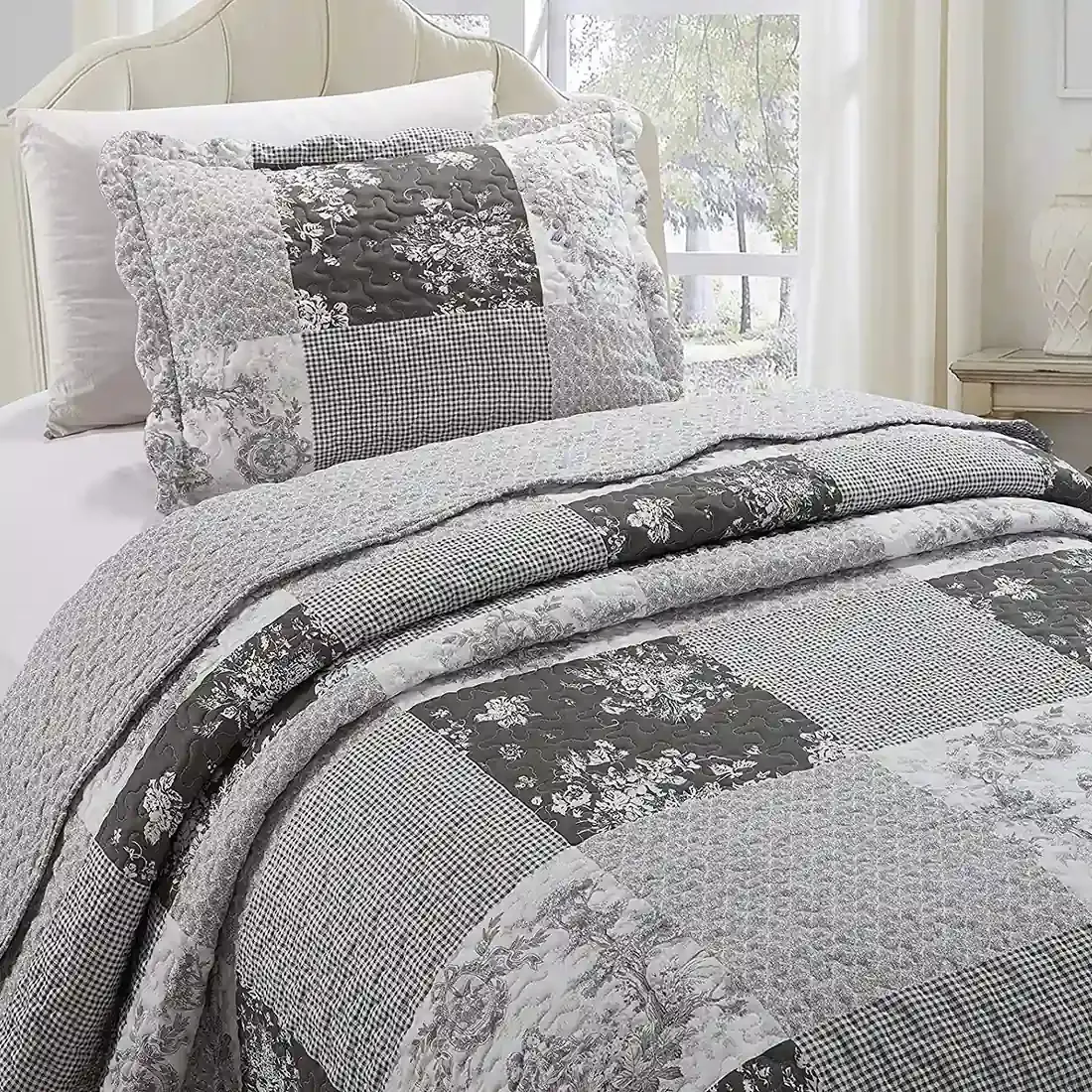 Een grijze kussensloop met bijpassende sprei op een knus bed bij het raam.