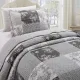 A patchwork pillowcase with matching bedspread on a cozy bed by a window.