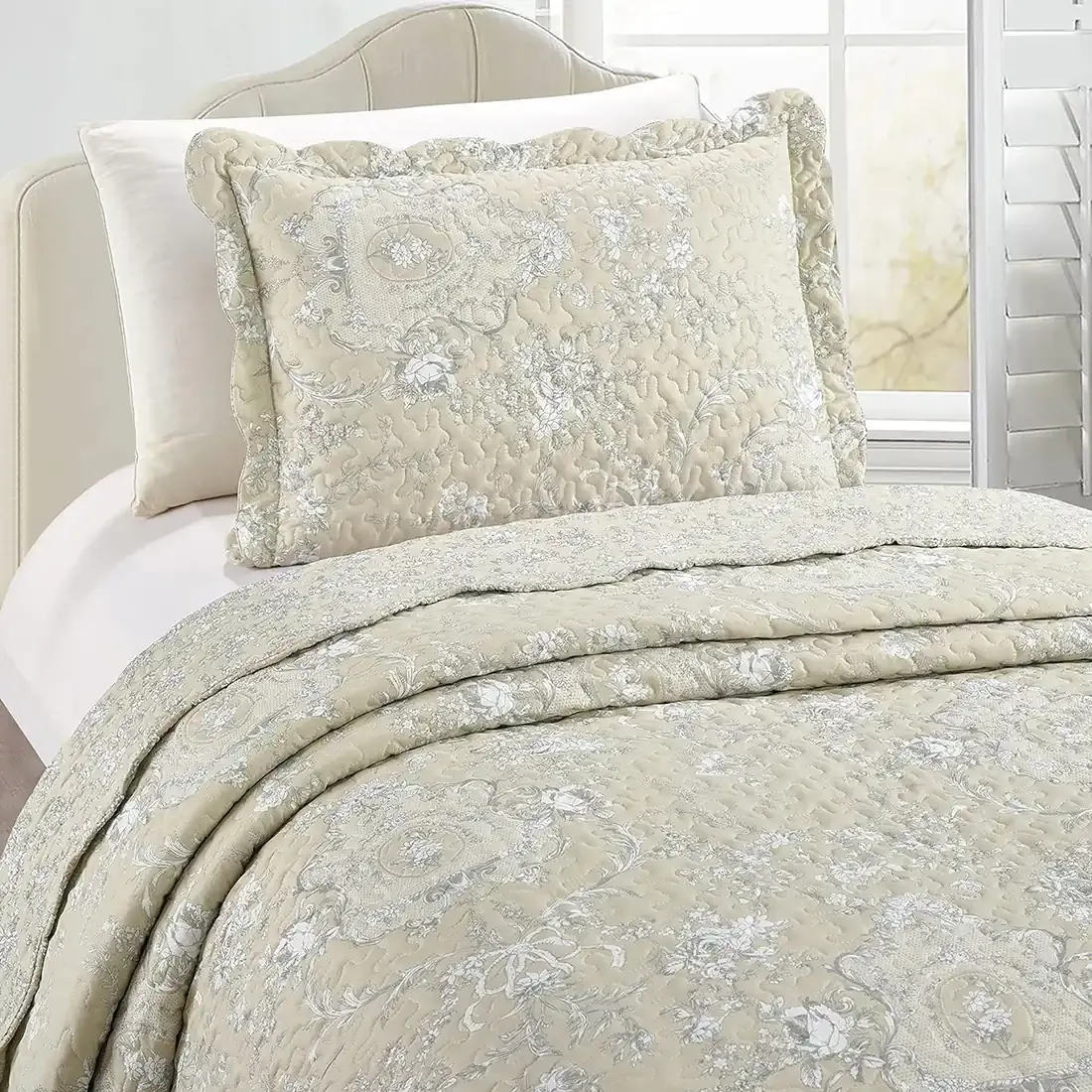 A Floral Toile pillowcase with matching quilt on a cosy bed by a window.