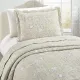 Een beige kussensloop met bijpassende sprei op een knus bed bij het raam.